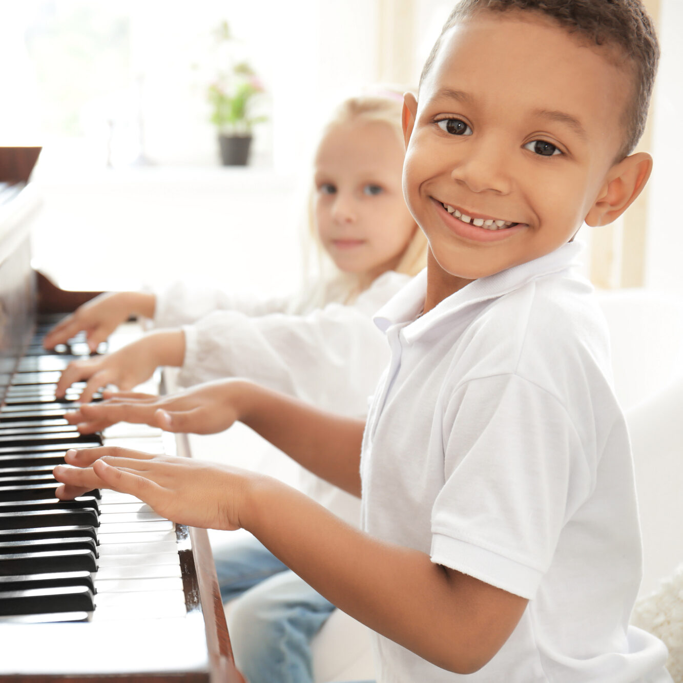 African-American boy with little girl playing piano indoors Group piano lessons at Melody Magic Music in Richmond VA